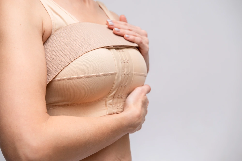 Patient wearing a post-operative compression bra supporting healing and recovery after breast augmentation surgery.